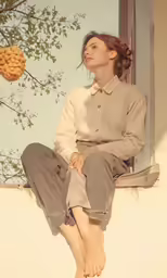 a person sits on a window ledge and looks out