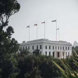 flags flying at half masts above a white building
