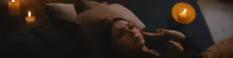 a woman lying in bed with a candle lit