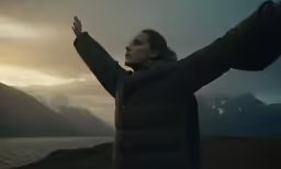 a person holds up their arms in the wind