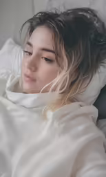 a woman in white is laying on a bed