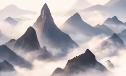 a mountain with several tall mountains next to a cloud covered landscape