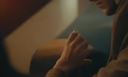 a woman wearing a brown jacket holding her cell phone