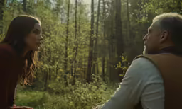 man and woman sit together in the woods