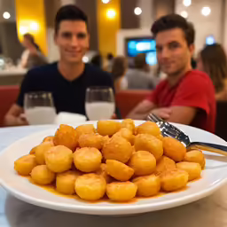 two people in a restaurant, one of them with a plate of tater tots