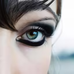 the woman is wearing an eyeliner with black make up on her eyelashes