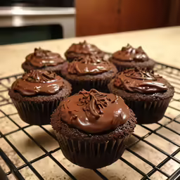 chocolate cupcakes with frosting on top sitting on a wire rack