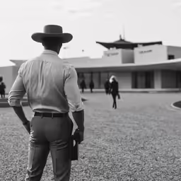 a person with a cowboy hat looks at people walking in the background