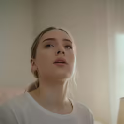 a beautiful young woman standing next to a window