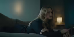 a woman laying on the couch wearing a dark colored jacket