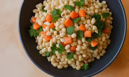 a black bowl containing vegetables and rice