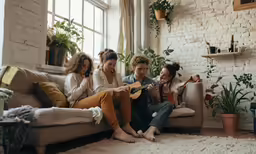 a group of friends sitting on a couch playing musical instruments