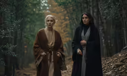 the two women are in a forest, one wearing a nun costume