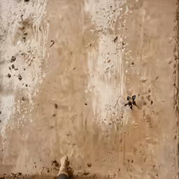 a man laying down next to a window covered in dirt
