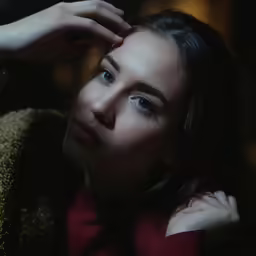 a woman is holding her hand up to her face