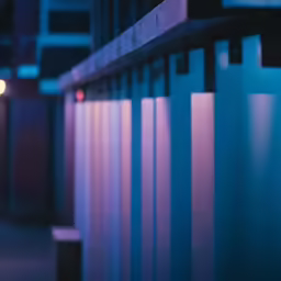 an illuminated clock on a building with vertical slats