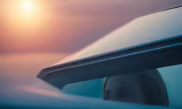 the side view mirror on a car shows the sun setting