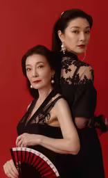 two women in black, one holding a red and white fan,a woman holding a fan and another woman