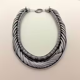 this is a long black and white necklace with intricate designs,a necklace is hanging on a white surface,two circular shaped items on a plain white background,three necklaces on display on a table,a three stranded necklace is hung from a hook