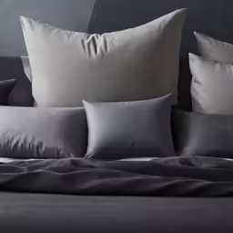 four pillows sitting on top of a bed next to each other