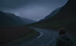 a person walking down a road in the middle of mountains