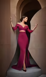a woman in a long red dress posing in front of a stone structure