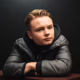a man that is sitting down wearing a jacket