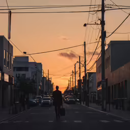 a man walking down the street holding a piece of luggage at sunset