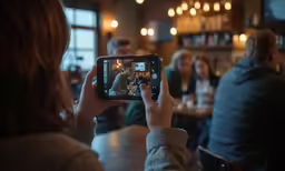 person taking pictures of a group at a bar