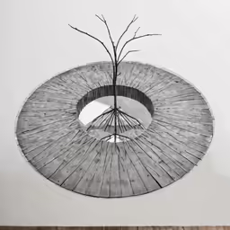 a tree in the middle of a circular object that is attached to a wall