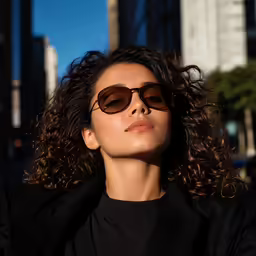 woman in sunglasses on street corner staring off into the distance