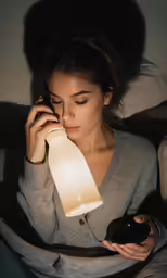 a woman holding a light up to her face