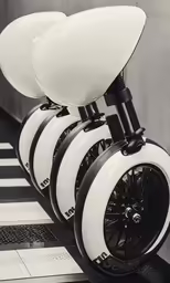 a white scooter with two black wheels is lined up on a street
