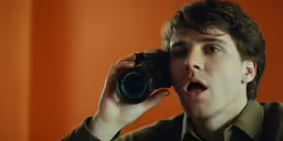 a young man holding a camera up to his face