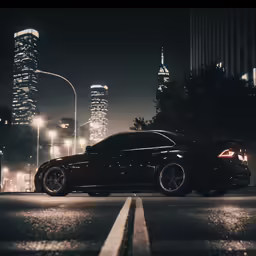 two car parked on the side of the street with buildings and lights in the background