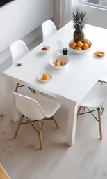 a white kitchen table with chairs and plates of food