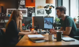 two people are talking at the table in the office