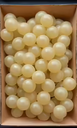 the inside of a brown box filled with white grapes