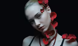 a woman with necklaces that have red flowers in the middle of her head