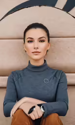 a woman sitting on a wall in front of a round object