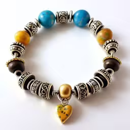 an orange, yellow and blue bead bracelet is decorated with hearts and beads,a bracelet with a yellow heart and two bead charms
