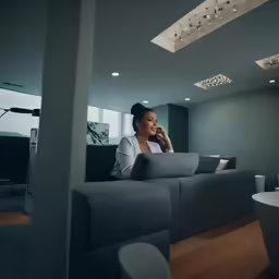 the woman is sitting on a grey sofa