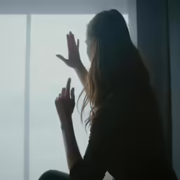 a woman making the hand gestures in front of a window