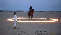 two horses and riders, one is fully clothed with flames