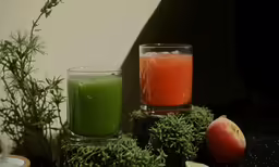a bottle of juice next to two glasses of juice
