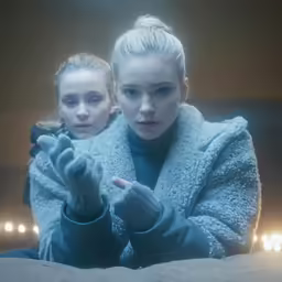 two women on a bed with lights behind them