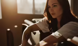a woman wearing white shirt and jeans sitting in front of window
