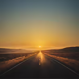 an empty road in the middle of nowhere with the sun behind