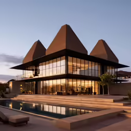 the exterior of an modern house is lit up at dusk