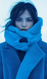 a woman with her hair in the wind is wearing a scarf